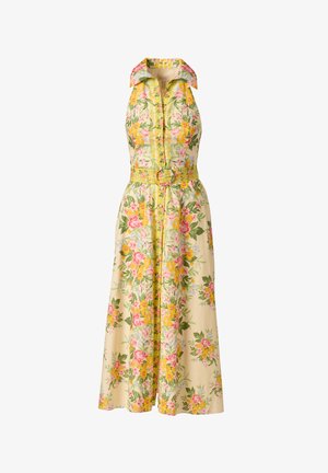 Żółta sukienka w kwiaty bez rękawów, z kołnierzykiem, zapinana na guziki z przodu i dopasowanym paskiem z okrągłą klamrą, do kolan, z różowymi, zielonymi i białymi wzorami kwiatów.