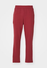 Rote Baumwoll-Jogginghosen mit elastischem Bund, geradem Schnitt, seitlichen Taschen und dezentem Logo auf dem linken Bein.