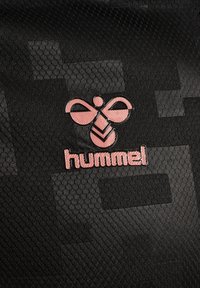 Svart texturerad tyg med en rosa logotyp av en stiliserad bi och ordet "hummel" i ett modernt typsnitt, med en glänsande yta.