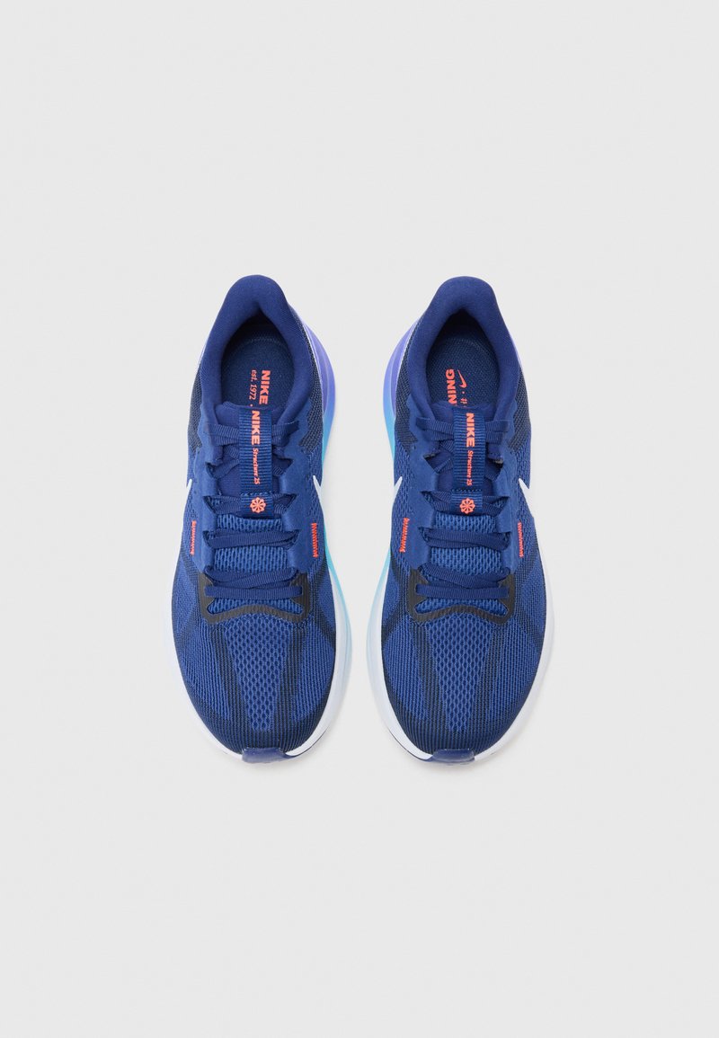 Zapatillas deportivas azul con parte superior de malla, tejido texturizado y suela blanca. Las características incluyen cordones, logo de Nike y vibrantes acentos en color naranja.