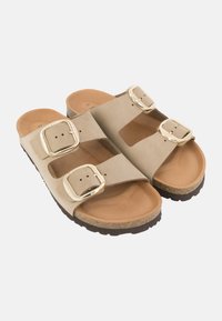 Sandali in suede beige con due cinturini larghi, fibbie dorate e una suola marrone testurizzata. Presentano un plantare imbottito per il comfort.