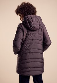 Puffjacka i mörklila, med huva, quiltad struktur och medellång design. Snygg, rak skärning med dolda dragkedjefickor.