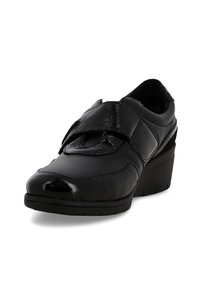 Scarpa wedge nera con tomaia sintetica lucida e liscia e una larga fascia in velcro sul davanti. Punta arrotondata e suola texturizzata.