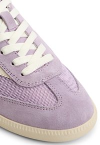 Sneaker viola in suede con dettagli in rete, lacci crema e suola in gomma testurizzata. Presenta una punta arrotondata e un motivo a battistrada triangolare.