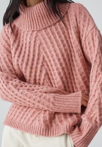 Sweter z warkoczowym splotem w delikatnym różu, z wysokim kołnierzem, posiadający ściągacze na rękawach i fakturowany wzór. Elastyczne mankiety zapewniają ciasne dopasowanie.