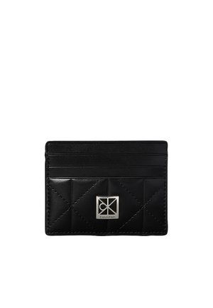Porte-cartes en cuir noir avec motif matelassé, quatre emplacements pour cartes et plaque logo Calvin Klein argentée à l'avant.