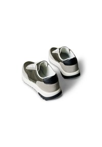 Sneaker bestehen aus einer Mischung aus olivgrünem Wildleder, schwarzen Lederelementen und weißen Schnürsenkeln, mit einer strukturierten Sohle für besseren Halt.