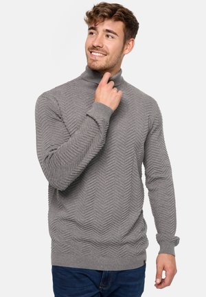 Pull à col roulé gris avec un motif texturé en zigzag, des poignets et un ourlet côtelés. Le tissu semble doux et chaud, adapté aux temps plus frais.