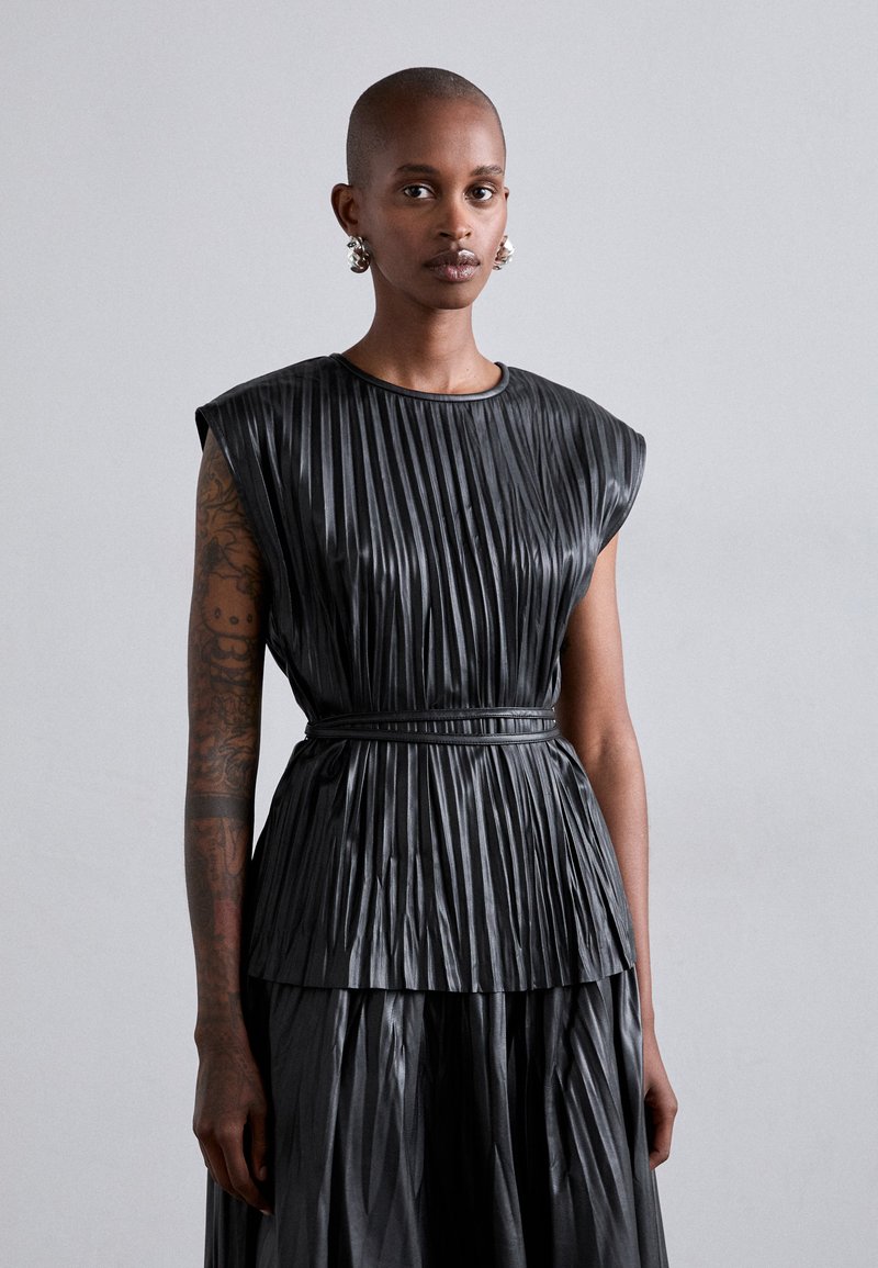 Schwarzes, gefälteltes Oberteil mit rundem Ausschnitt und breitem Schulterdesign, ausgestattet mit einem Gürtel in der Taille. Glatte, glänzende Textur mit einem schichtartigen Look.