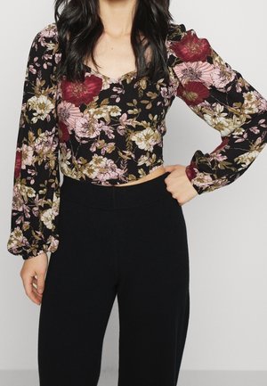 Black floral crop top with puffed sleeves, featuring pink and burgundy flowers, paired with high-waisted black fitted pants.