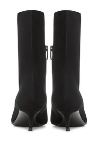 Botas de tobillo de ante negro con tacón alto, que cuentan con una textura suave y dos cierres de cremallera laterales. Punta cuadrada y silueta elegante.