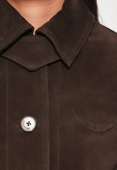 Brown suede jacket featuring a sharp collar, button closure, and decorative stitching on the chest with subtle wing-like accents.