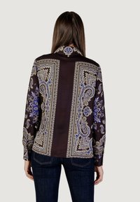 Blusa a maniche lunghe di colore marrone scuro, con una stampa paisley in blu e crema. Tessuto morbido con chiusura a bottoni al colletto.
