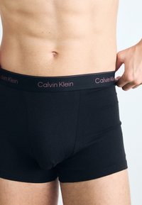 Boxeri din bumbac negru cu o textură netedă și un garnitură lată, având logo-ul "Calvin Klein" scris cu litere roz.
