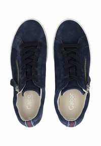 Navy semišové tenisky s bílou gumovou podrážkou, černými šňůrkami a bočním zipem. Interiér má světlou podšívku a značení.