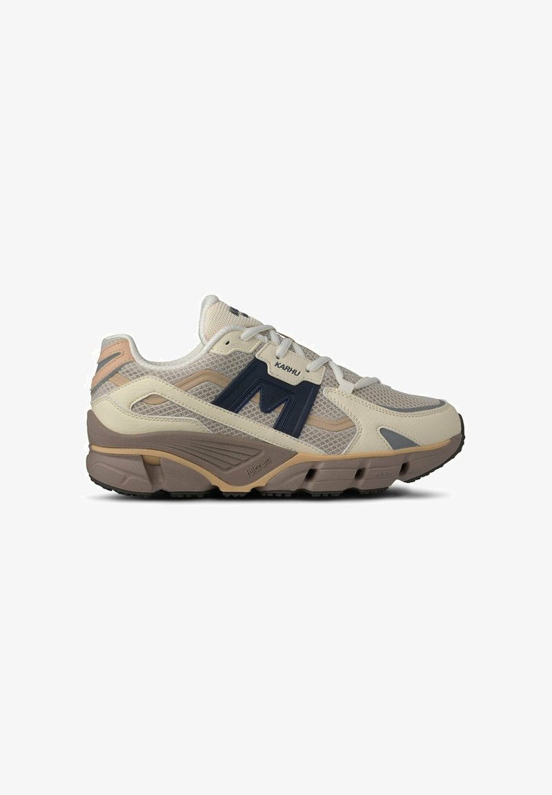 Beige Netz-Turnschuhe mit navyfarbigen Akzenten, ausgestattet mit einer gepolsterten Sohle, strukturierten Überzügen und minimalen rosa Details. Logo deutlich sichtbar.