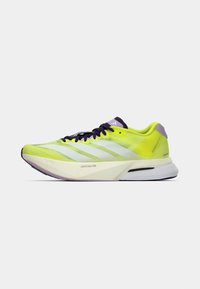 Zapatilla de running de color amarillo neón con parte superior de malla, rayas diagonales blancas, detalles en púrpura y una suela ligera blanca etiquetada como "LIGHTSTRIKE PRO."