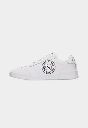 White low-top sneaker with black "Versace Jeans Couture" circular logo on side and heel tab, white laces, and white rubber sole.