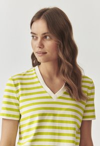 Hvid bomulds T-shirt med grønne vandrette striber, med v-hals og korte ærmer. Blød tekstur med et afslappet design.