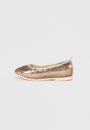 Zapatilla de ballet plana dorada cubierta de lentejuelas con una pequeña lengüeta en la parte posterior y una suela de color claro.