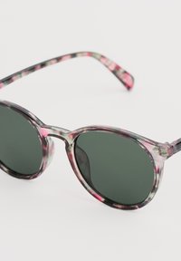 Transparente Sonnenbrillen mit einem gemusterten Rahmen in verschiedenen Rosa- und Grüntönen, runden Gläsern und schwarzem getöntem Glas.