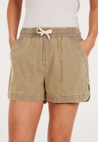Pantaloni corti khaki con vita elastica e coulisse, dotati di due tasche laterali e un tessuto leggermente strutturato. Accentuati da un'etichetta.