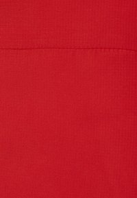 Tessuto rosso con una texture liscia, caratterizzato da una sottile costina verticale. Nessun motivo o accessorio visibile, enfatizzando un design a tinta unita.