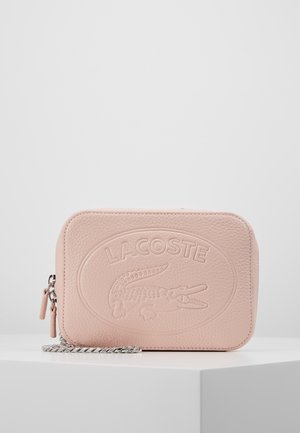 Blød pink tekstureret læder Lacoste clutch med præget logo og krokodilledesign, med sølvkæde og dobbelte lynlåse.