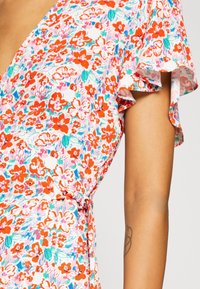 Vestito avvolgente floreale con sfondo bianco e fiori rossi, rosa e turchesi. Maniche arricciate e dettaglio con cintura in vita. Tessuto leggero.