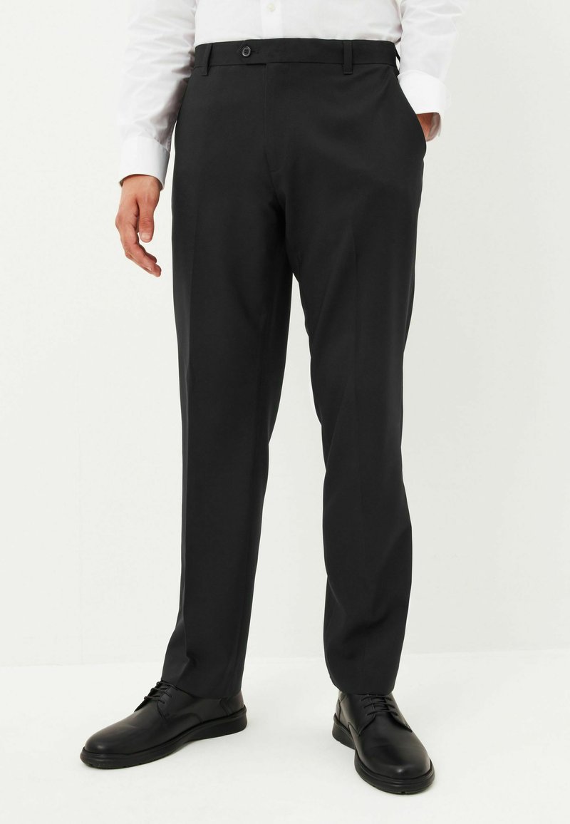 Musta räätälöity housut, jotka on valmistettu sileästä kankaasta, varustettu napilla, sivutaskuilla ja suoralla lahkeella, yhdistettynä mustiin kenkiin.