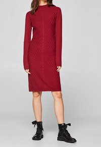 Langärmliges, burgunderfarbenes Strickkleid mit gerippter Textur und diagonalen Streifen, kombiniert mit schwarzen Schnür-an Kle Boots.