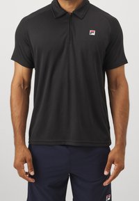 Czarna koszulka polo z krótkim rękawem, z półzamkiem, w pionową prążkowaną teksturę oraz małym logo na lewej piersi. Odpowiednia do codziennego noszenia.
