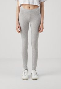 Gray leggings made of soft, stretchy fabric, featuring a high waistband, slim fit, and ankle-length design paired with white sneakers.