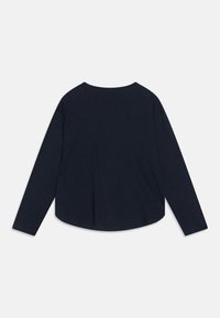 Námořnická modrá košile s dlouhým rukávem a kulatým výstřihem, vystavená ploše s zadní stranou nahoru na bílém pozadí.