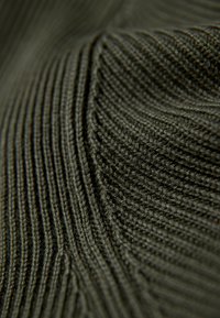 Dunkelgrüner gestrickter Stoff mit strukturiertem vertikalem Rippenmuster, das feine und mittlere Maschen zeigt, die ein wellenartiges Muster erzeugen.