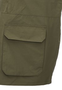Olivengrüner Stoff mit glatter Textur, ausgestattet mit einer großen aufgenähten Tasche und gestickten Details. Einfaches, funktionales Design.