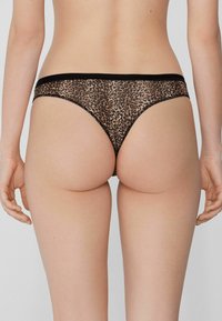 Leopardprint slipje van een zachte stof, met een zwarte elastische tailleband en een minimalistisch ontwerp, dat de lage taille en naadloze pasvorm benadrukt.