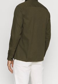 Olivgrünes Hemd mit Knopfleiste, Kragen, langen Ärmeln und geknöpften Manschetten, aus einem glatten Stoff mit lockerem Schnitt gefertigt.