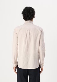 Camicia a maniche lunghe di un delicato rosa, realizzata in tessuto texture, con un motivo sottile, polsini con bottone e un design posteriore semi-adattato.