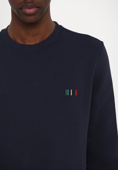 Sweatshirt bleu marine avec un col rond, présentant un petit design brodé avec des rayures verticales en vert, jaune, rouge et bleu.