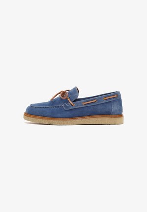 Blauwe suède loafer met bruine leren veters en een beige crepezool, zijaanzicht op witte achtergrond.