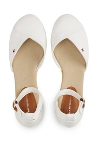 Witte canvas ballerina's met een ronde neus, enkelbandje en beige binnenzool. Bevat het merkelogo in het blauw, rood en wit aan de zijkant.