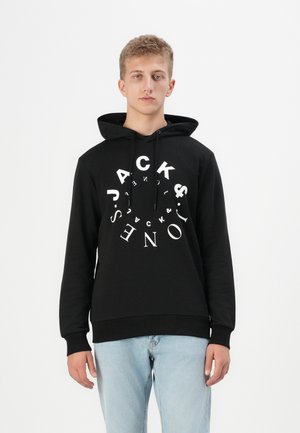Black hoodie with a kangaroo pocket and drawstring hood. Features oversized white text design in circular layout. Cotton blend material, relaxed fit.