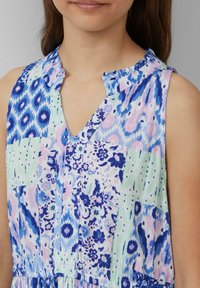 Mehrfarbiges ärmelloses Kleid mit einem Rüschenausschnitt, V-Ausschnitt und einem Patchwork-Design mit Blumen- und geometrischen Mustern in Blau, Grün und Pink.