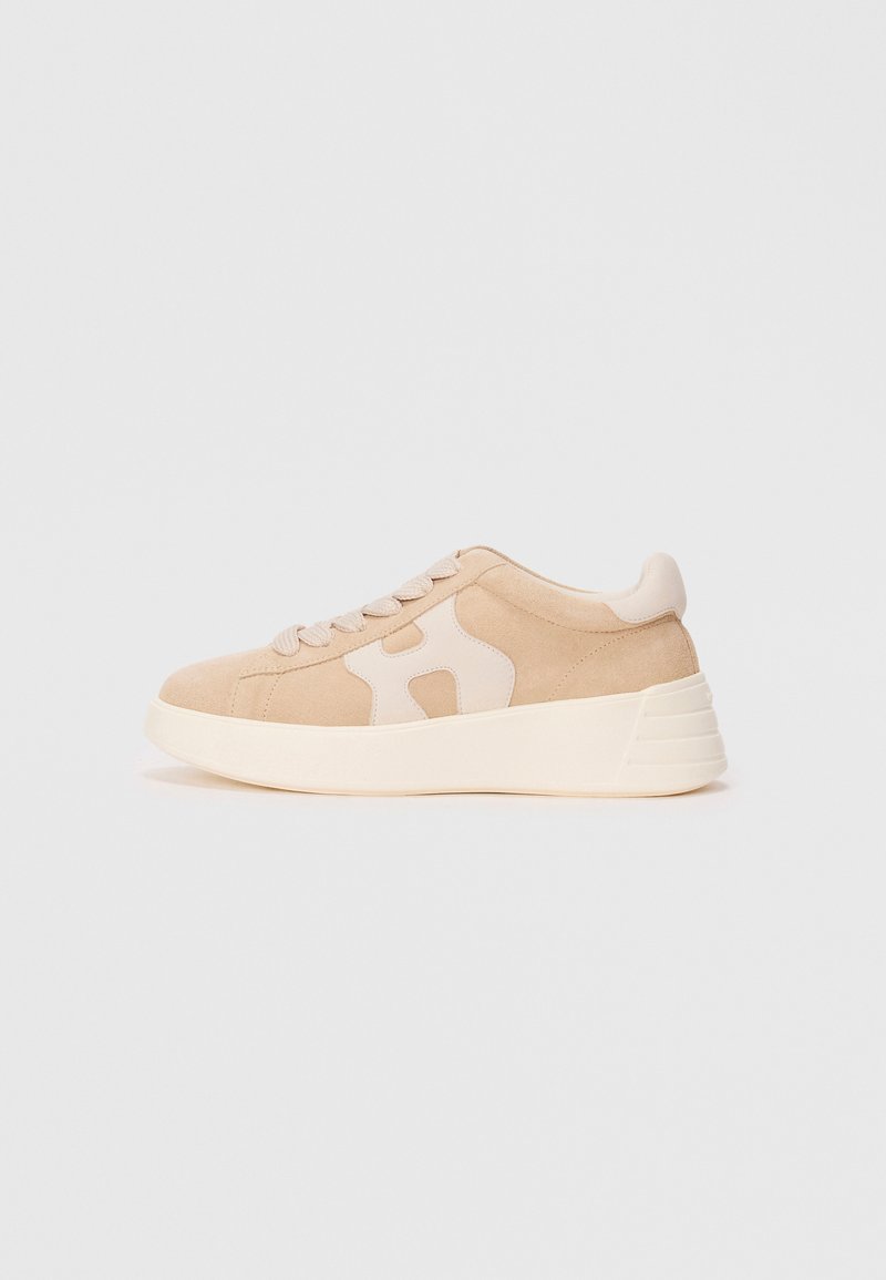 Baskets en suede beige avec une semelle épaisse blanc cassé, à lacets à l'avant et un logo en patch de couleur claire sur le côté, présentées en vue de profil.