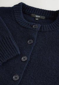 Cardigan blu navy realizzato in tessuto texturizzato, con colletto a coste, cinque bottoni neri e un'etichetta con il marchio "NEXT".