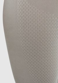 Beige Leggings mit einem strukturierten Wabenmuster auf einer Seite, aus dehnbarem Material und mit glatter Oberfläche.