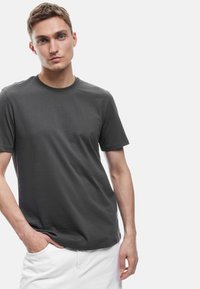 Mørkegrå bomulds T-shirt med rund hals og korte ærmer, med en glat tekstur og en afslappet pasform. Parret med hvide shorts.