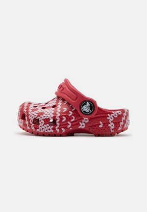 Rød slip-on træsko med hvidt strikket mønster, ventilationshuller og justerbar hælrem med rundt logodetalje.
