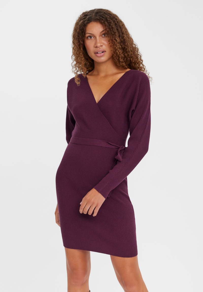 Robe enveloppante côtelée en violet foncé avec des manches longues, un col en V et un détail de taille à nouer, accentuant une silhouette ajustée.